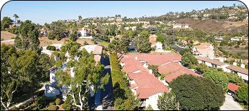 Bright daylight shot captured in aerial view of a residential area showing rooftop of houses along with bushy trees everywhere.