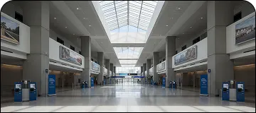 Interior view of Los Angeles International Airport (LAX) terminal with check-in counters and signage for LGB to LAX car service route.