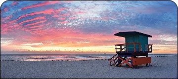 Picturesque sunset over Newport Beach harbor with yachts, calm water, palm trees, and coastal buildings for LGB to Newport Beach car service.