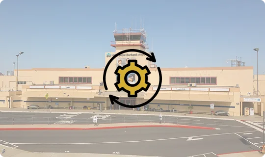 Exterior view of the Hollywood Burbank Airport terminal building under construction with scaffolding, featuring the control tower and clear blue sky.