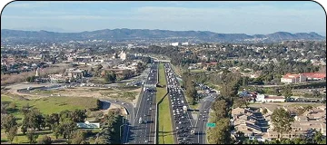 Aerial view along the San Diego to Temecula route of vineyards and rolling hills with a highway running through the landscape.