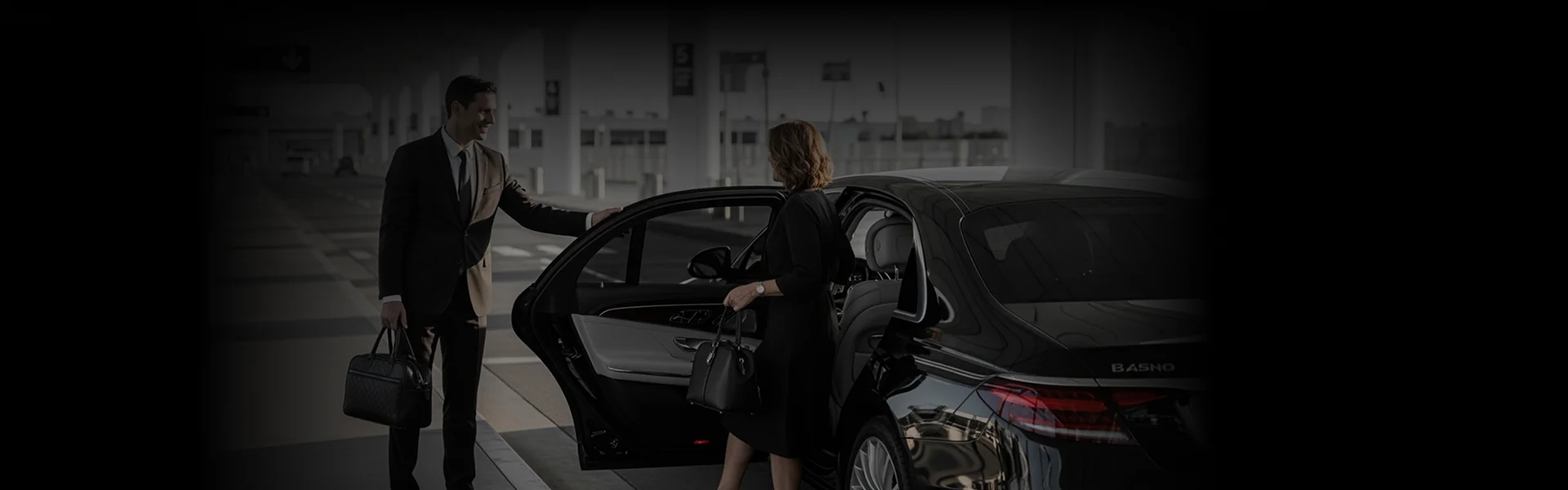 Chauffeur assisting a passenger into a luxury black sedan at the terminal, representing ONT Airport Car Service for professional and comfortable airport transfers.