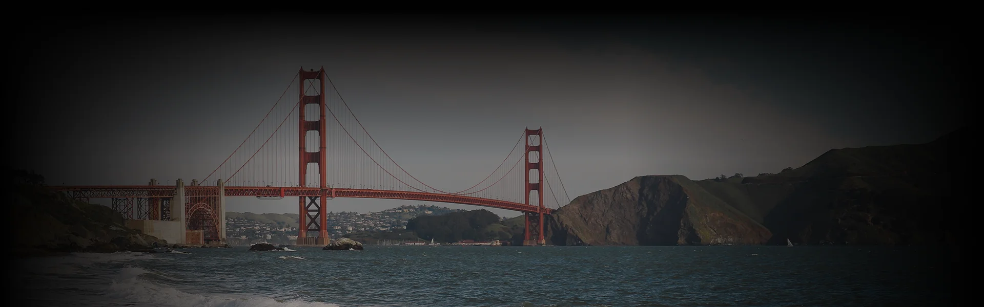 Golden Gate Bridge viewed from the water at eye level under soft daylight, with “San Francisco Car Service” text overlay promoting luxury travel tied to this iconic landmark.
