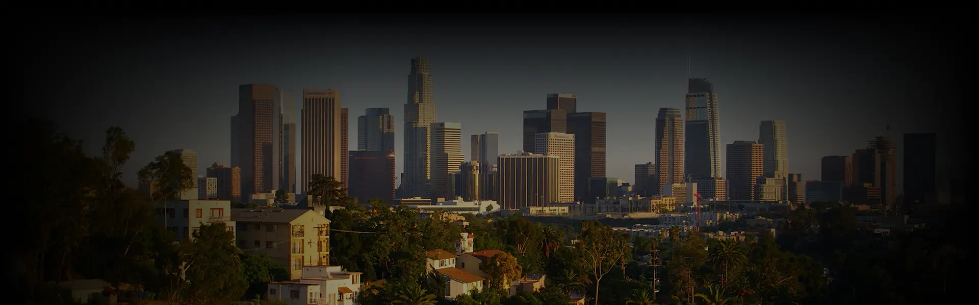 Skyline view of downtown Los Angeles under a warm golden glow, captured from an elevated angle, representing luxury Car Service California.